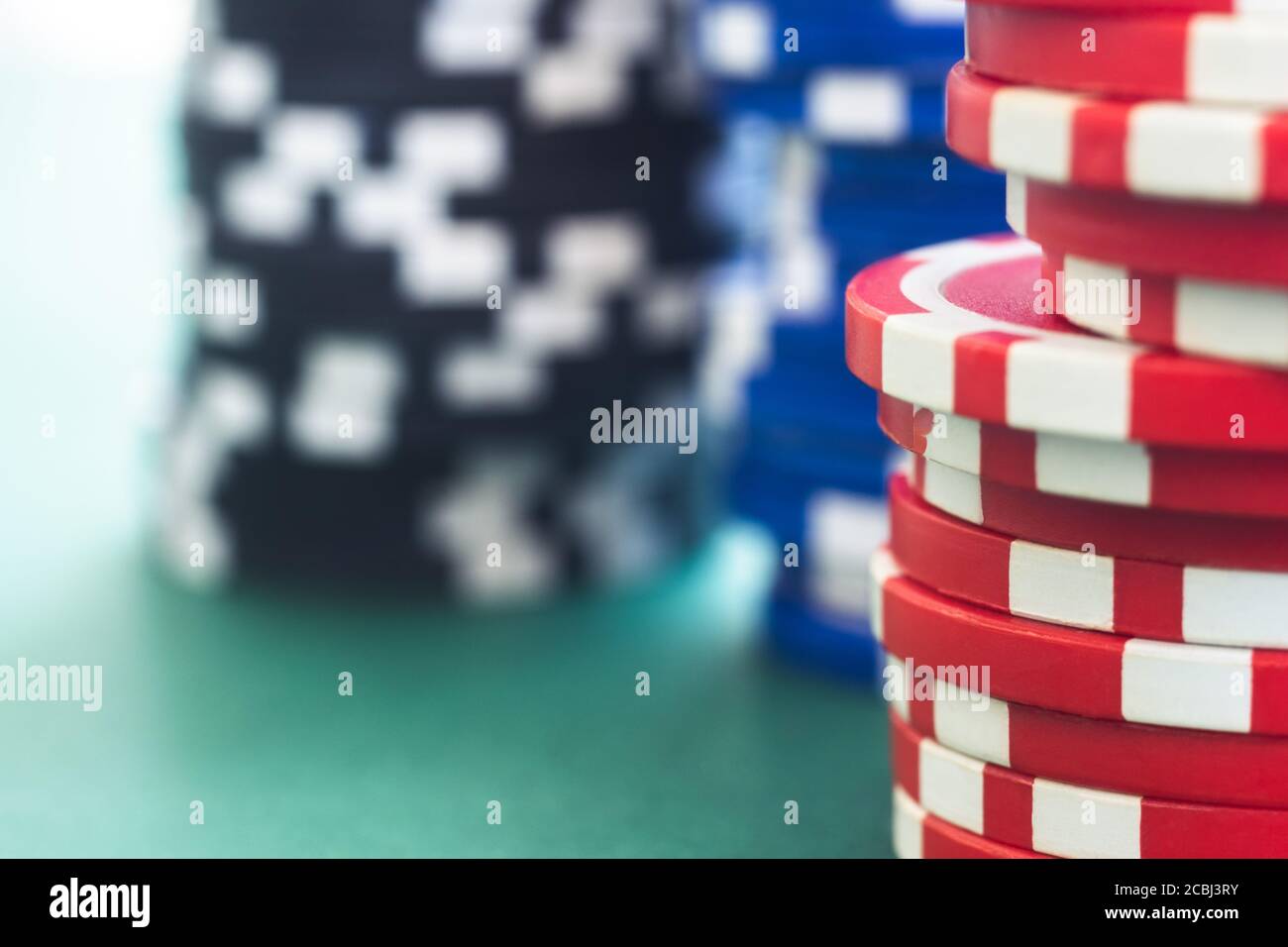 Pile di chip di gioco sul verde feltro tavolo, sfocato Foto Stock