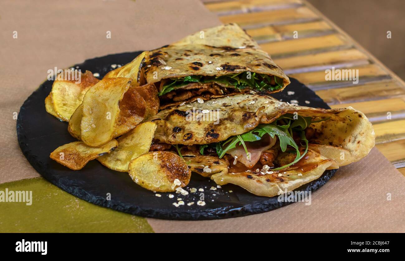 Piadina o piada, pane piatto italiano sottile con manzo, rucola e patatine Foto Stock