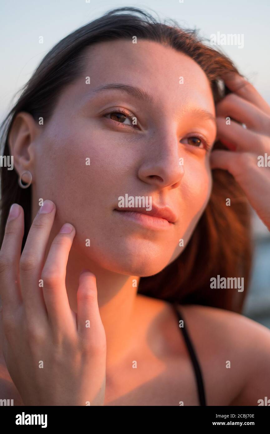Brunetta che tocca il viso e guarda lontano Foto Stock