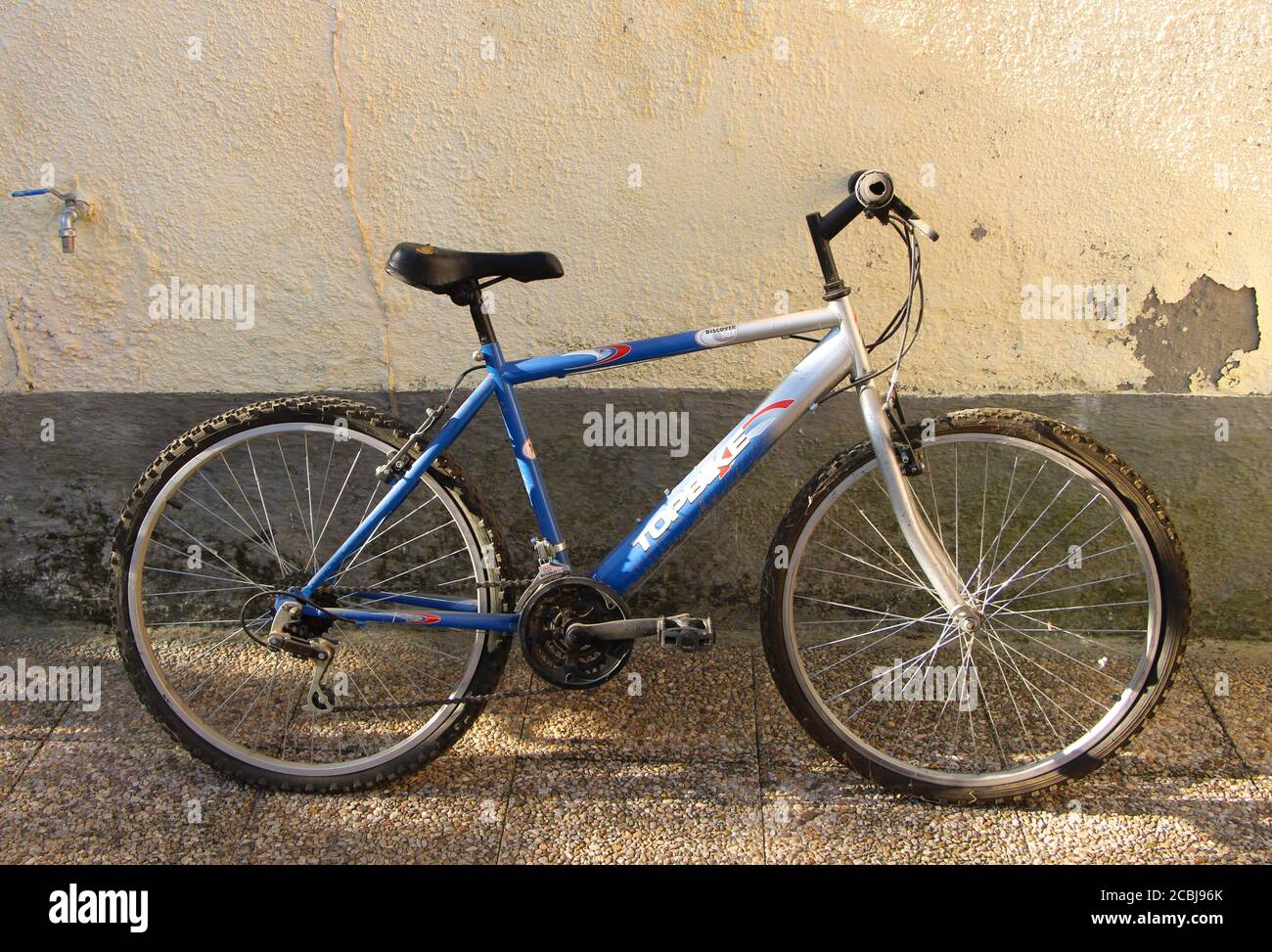 Foto di una bicicletta Topbike con pneumatici piatti e nastri di ciottoli  in piedi contro una parete dipinta di giallo e grigio Lantadilla Palencia  Spagna Foto stock - Alamy