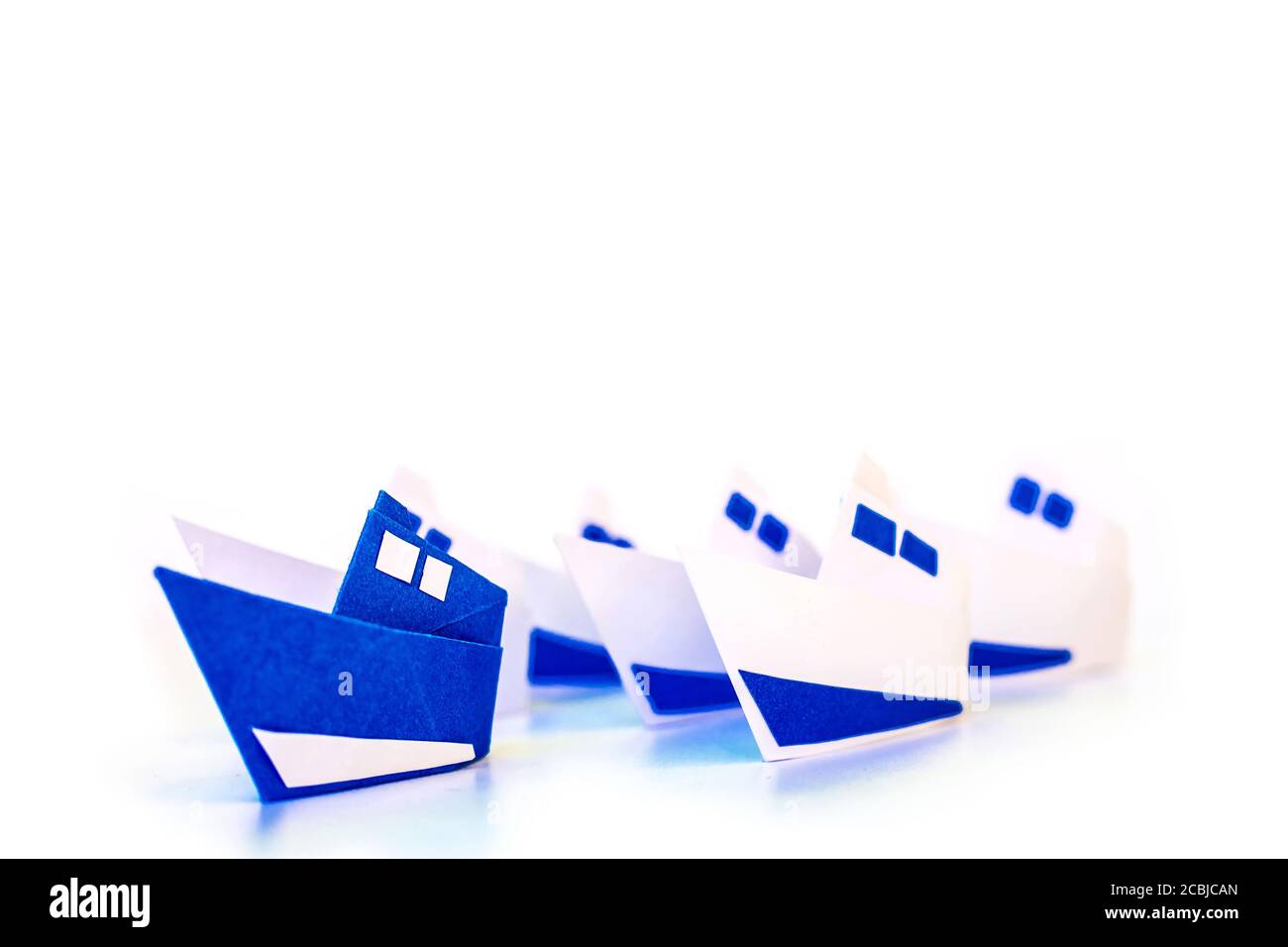 Concetto di leadership con la spedizione di carta blu leader tra il bianco. Foto Stock