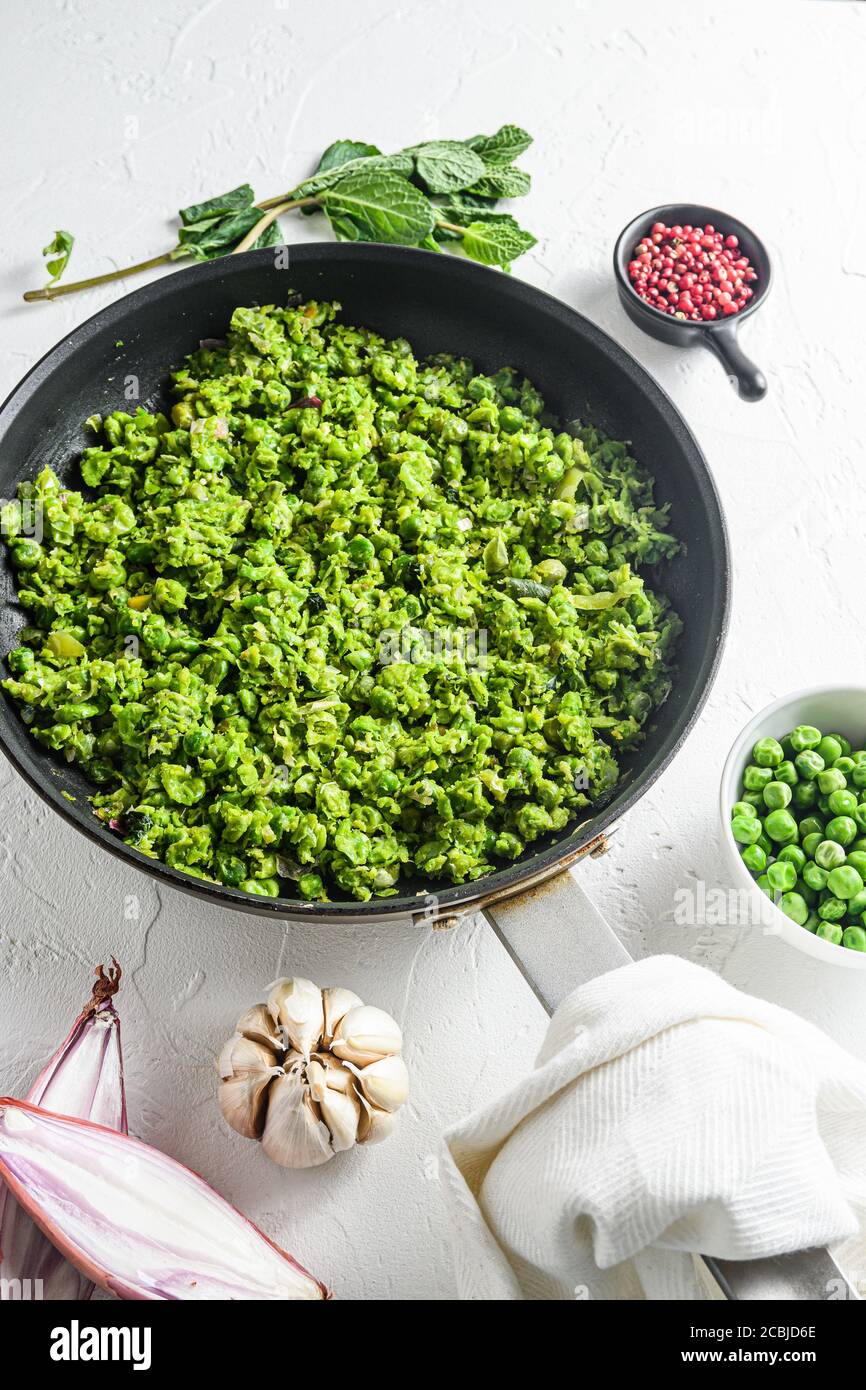 Ricetta di piselli ai funghi padella cotti e piselli in ciotola con pepe di scalogno di menta e sale su una superficie di pietra bianca vista laterale del keto food biologico Foto Stock