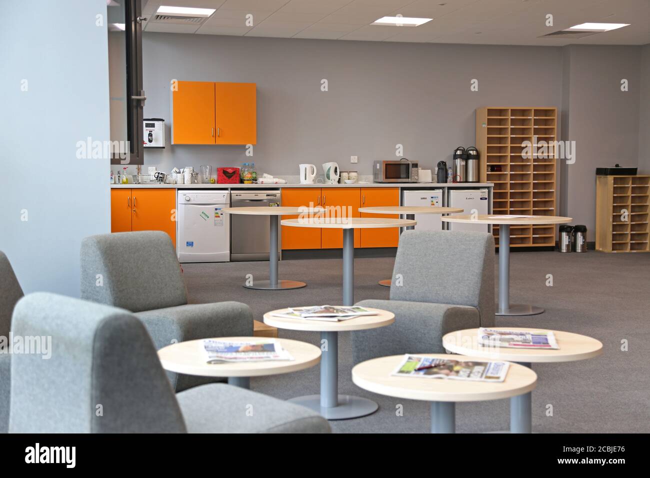 Camera del personale in una scuola secondaria di Londra appena completata. Presenta un'area cucina con frigoriferi e lavastoviglie e un'area salotto in primo piano. Foto Stock