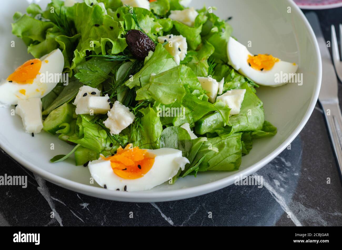 Insalata di verdure fresche con lattuga, aneto, porslane, pepe, formaggio, uova e olive nere Foto Stock