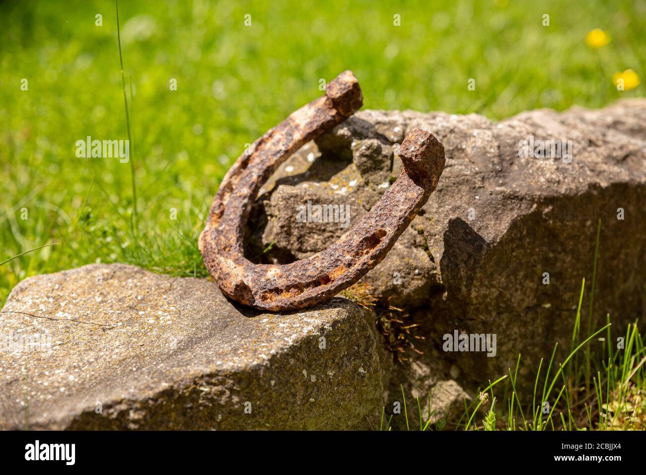 Un vecchio ferro di cavallo arrugginito proppato su una grande pietra. Simbolo di felicità e fortuna. Foto Stock