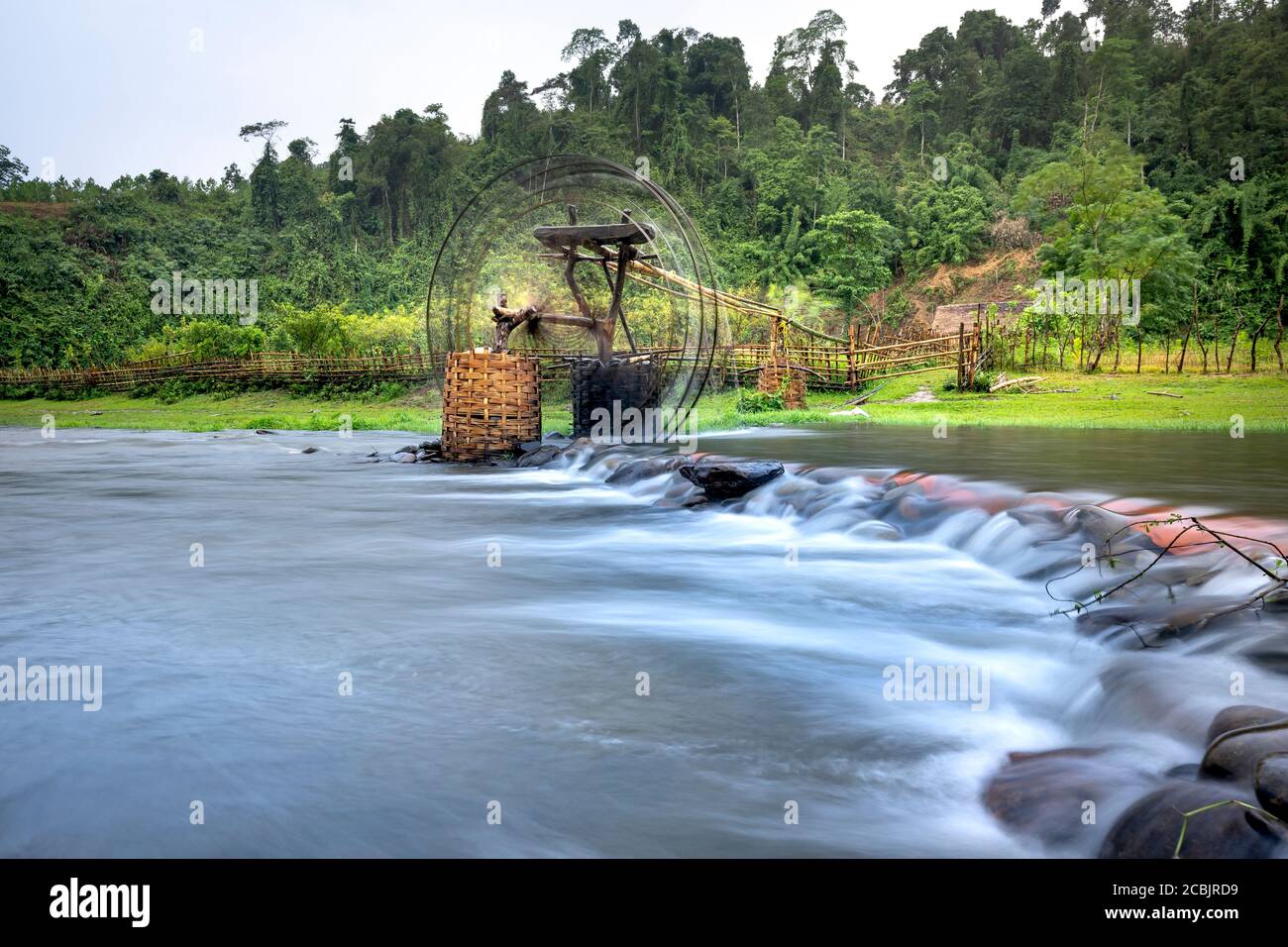 La ruota di acqua di bambù ottiene l'acqua dal ruscello per irrigare i campi di riso. Paesaggio speciale della regione Nghe An provincia montagne, Vietnam. Foto Stock