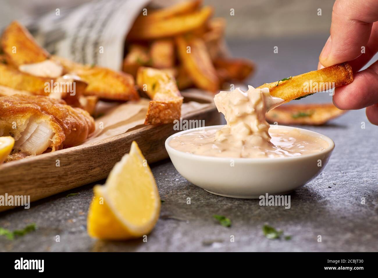 Tenere a mano una patatine fritte e immergerla in salsa tartaro Foto Stock