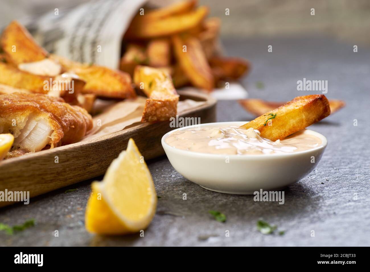 Un pezzo di patatine fritte lo immerge in tartaro di salsa Foto Stock