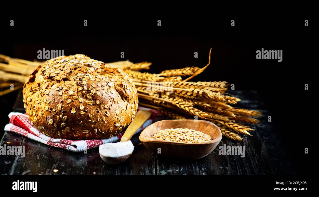 Pane fresco francese baguette, farina biologica e grano integrale su tavola di legno scuro d'epoca. Pane tradizionale al forno. Sfondo del menu del negozio di panetteria. Foto Stock