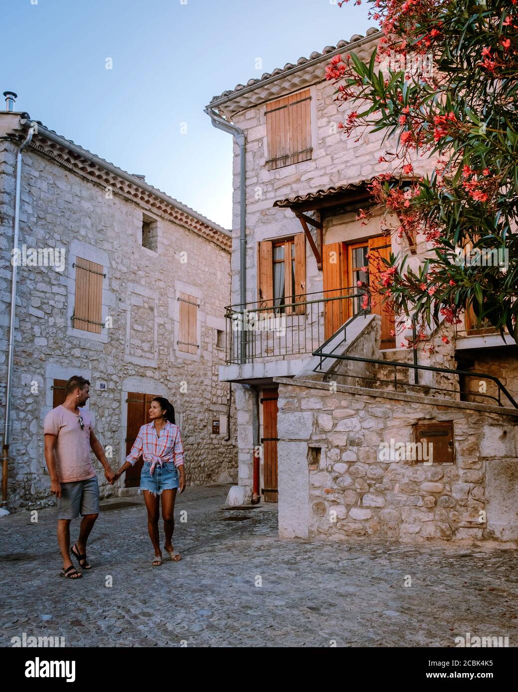 Una coppia visita Ruoms, il borgo medievale di Ruoms con le sue vecchie case in mattoni e i piccoli vicoli sul fiume Ardeche in Francia Foto Stock