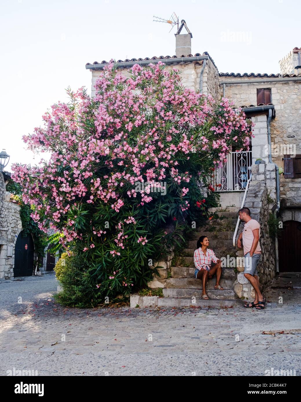 Una coppia visita Ruoms, il borgo medievale di Ruoms con le sue vecchie case in mattoni e i piccoli vicoli sul fiume Ardeche in Francia Foto Stock