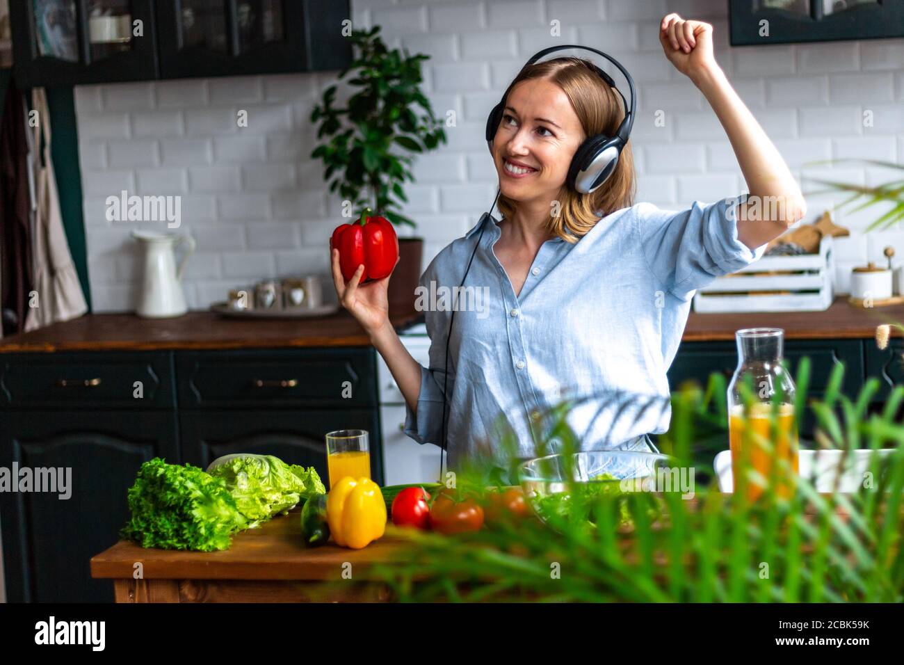 Donna danzante in cuffia in cucina cucinando verdure sane Foto