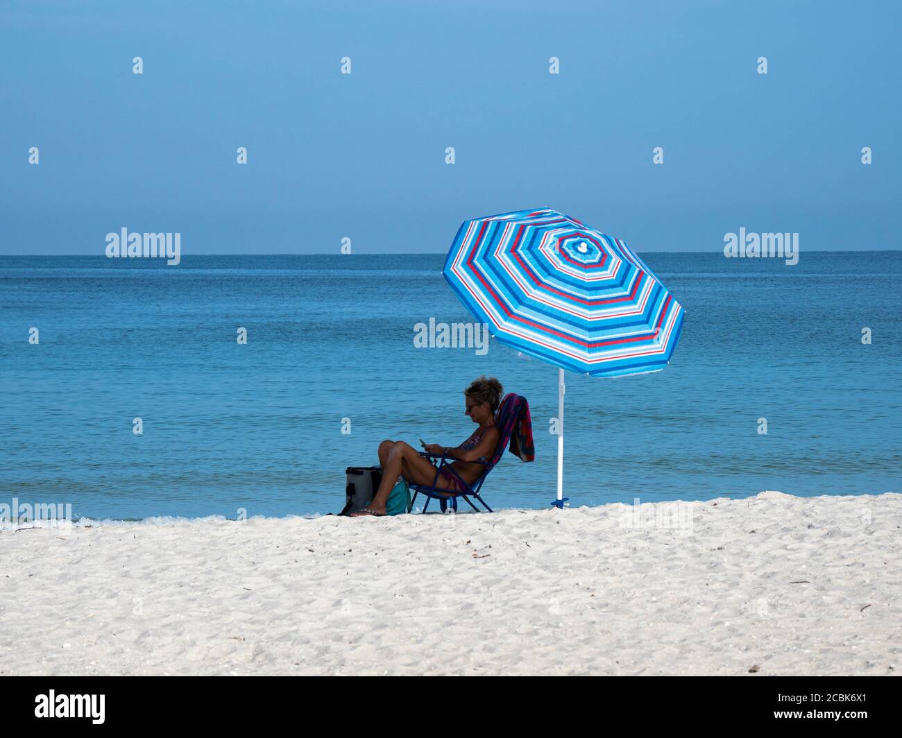 Donne sedute in sedia da spiaggia sotto la Cumbella sulla spiaggia in Florida negli Stati Uniti Foto Stock