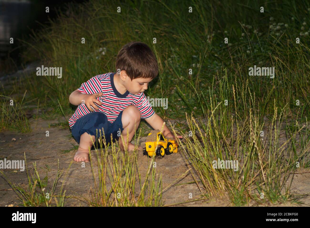 Un bambino in natura gioca con i giocattoli. Aria fresca in estate di infanzia. Foto Stock