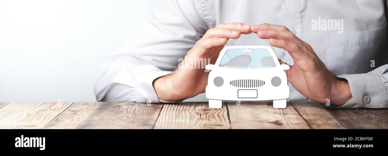 Proteggere le mani sopra l'icona dell'automobile sulla tabella di legno - assicurazione dell'automobile Concetto Foto Stock