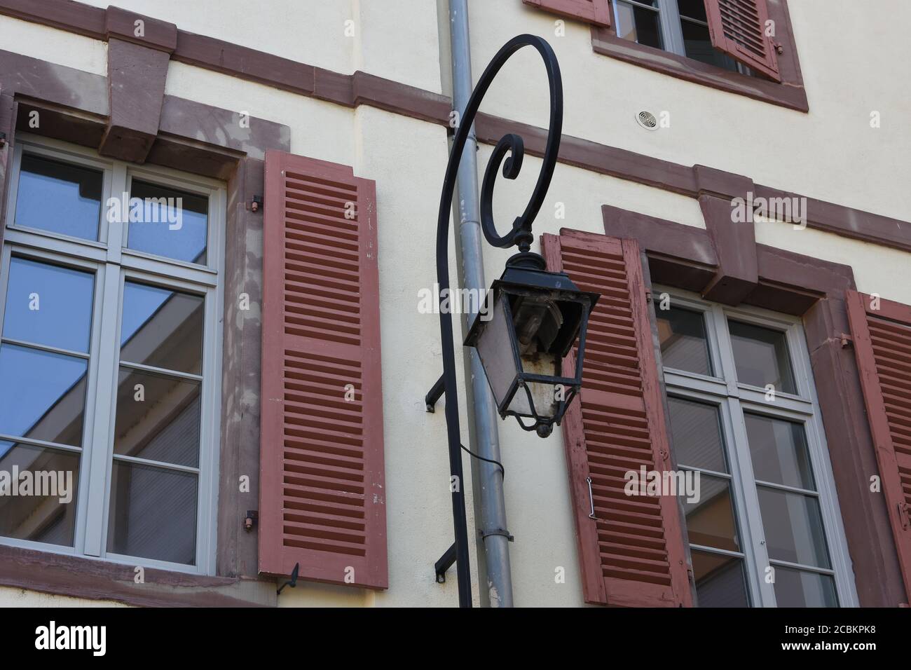 Vetro rotto della vecchia lampada da strada con nuova lampadina nella facciata allegata di un vecchio edificio residenziale nel centro di Colmar, Francia. Foto Stock