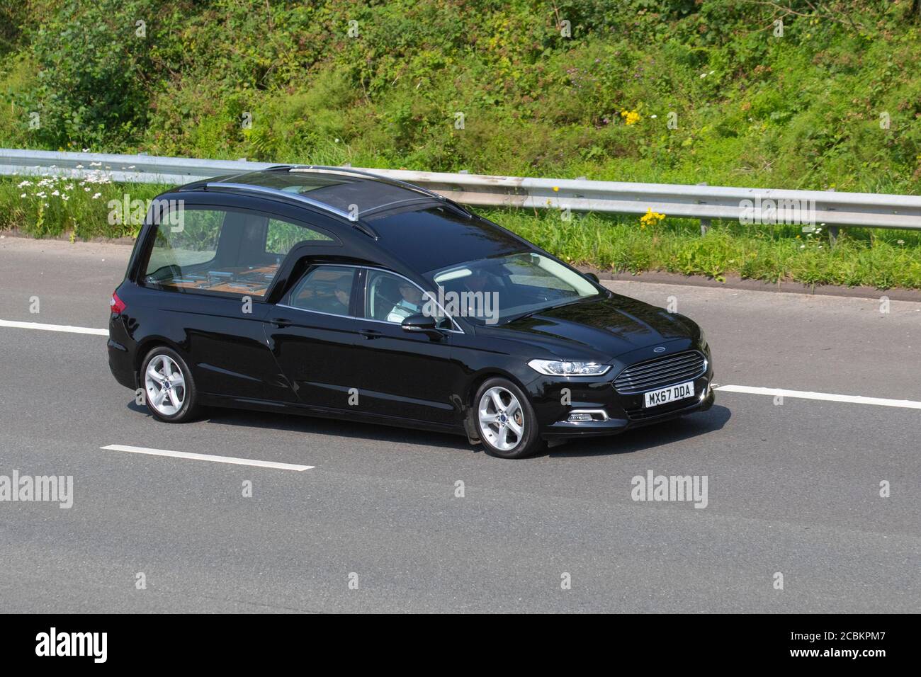 Coleman Milne Norwood Auto Black hearse; veicoli veicolari in movimento, automobili che guidano veicoli su strade del Regno Unito, motori, motori sulla rete autostradale M6. Foto Stock