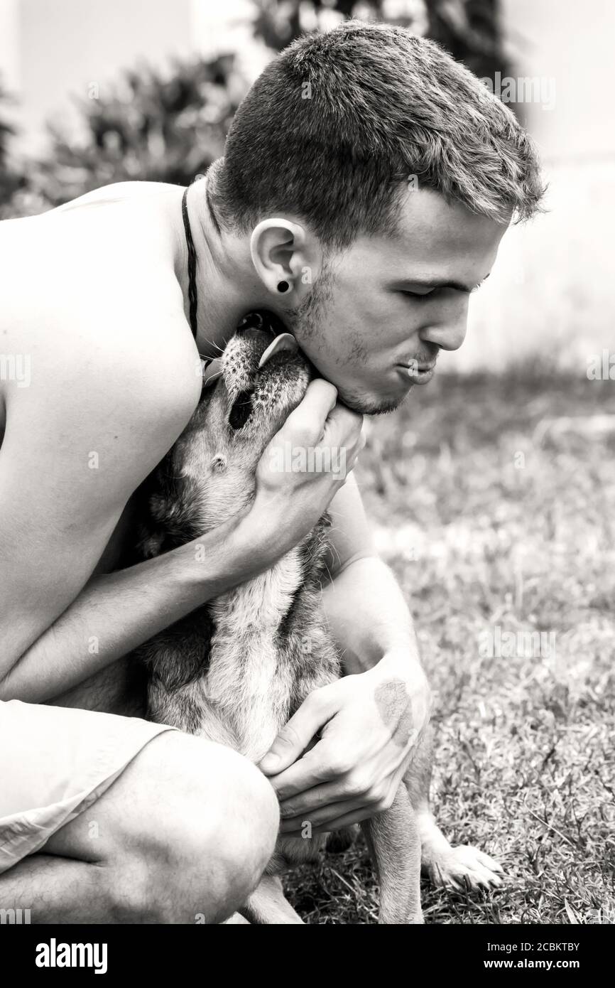 Giovane maschio abbracciando il suo cane quando si salutano l'un l'altro all'aperto. Foto Stock