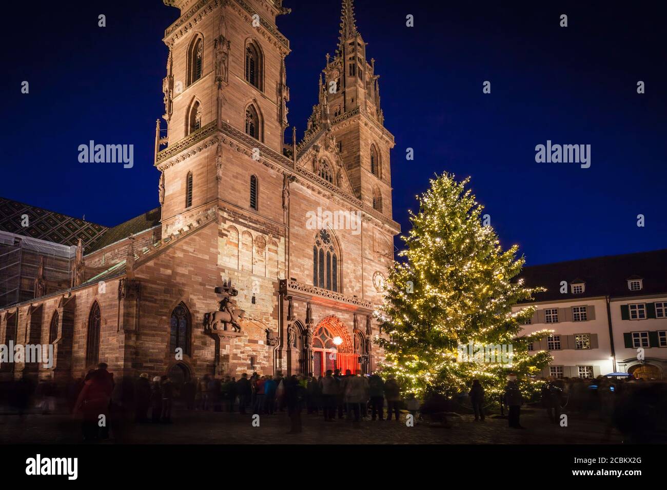 Folle di persone intorno all'albero di Natale illuminato da chiesa, Basilea, Svizzera Foto Stock
