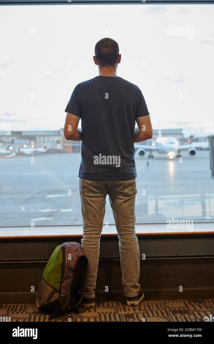 Vista posteriore dell'uomo che guarda fuori dalla finestra dell'aeroporto Foto Stock