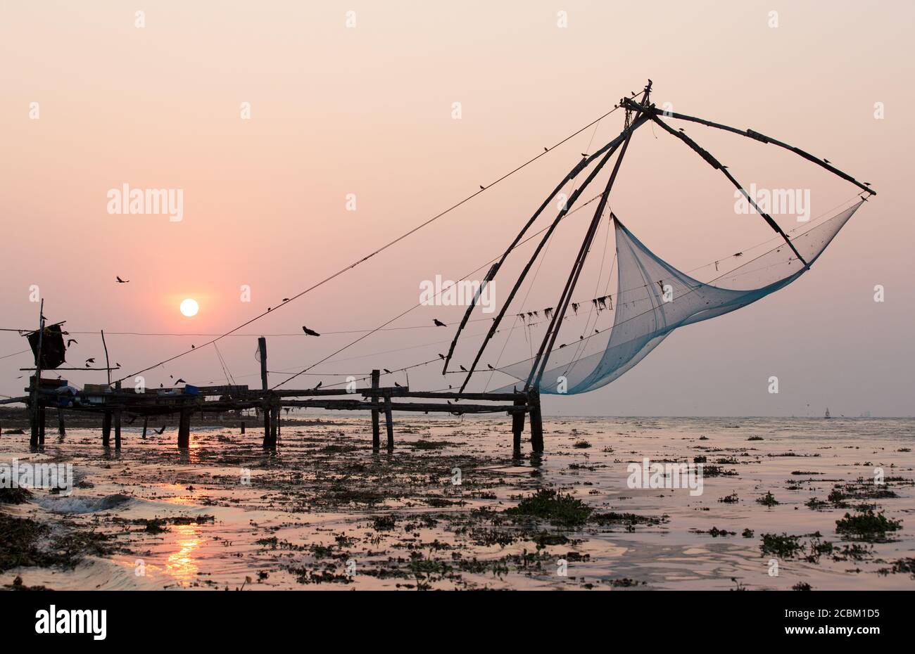 Molo e reti da pesca sulla spiaggia al tramonto, Kochi, Kerala, India Foto Stock