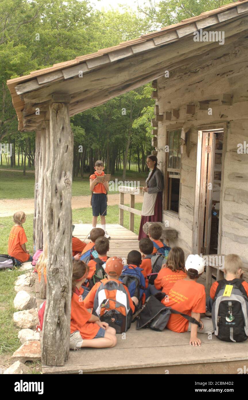 Austin, Texas USA, maggio 2006: Gli studenti di terza classe ascoltano sul portico della scuola di una stanza, mentre gli studenti leggono dal vecchio libro di testo durante il viaggio scolastico in campo alla fattoria restaurata del XIX secolo. ©Bob Daemmrich Foto Stock