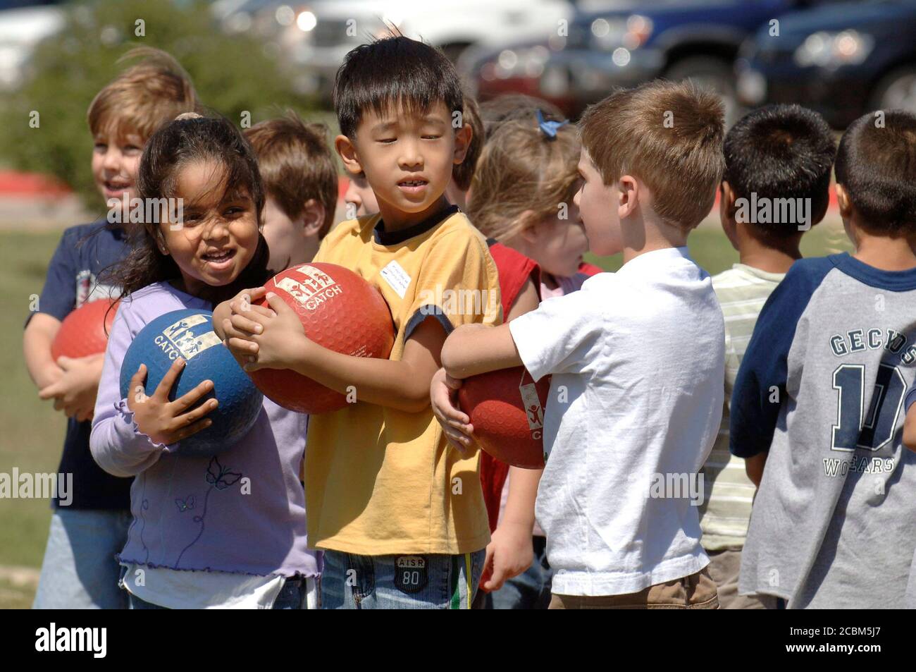 Round Rock, Texas: Gruppo multietnico di studenti di asilo tenere le palle durante la pratica di kickball in classe di educazione fisica alla scuola elementare. ©Bob Daemmrich Foto Stock Round Rock, Texas: Gruppo multietnico di studenti di asilo tenere le palle durante la pratica di kickball in classe di educazione fisica alla scuola elementare. ©Bob Daemmrich Foto Stock
