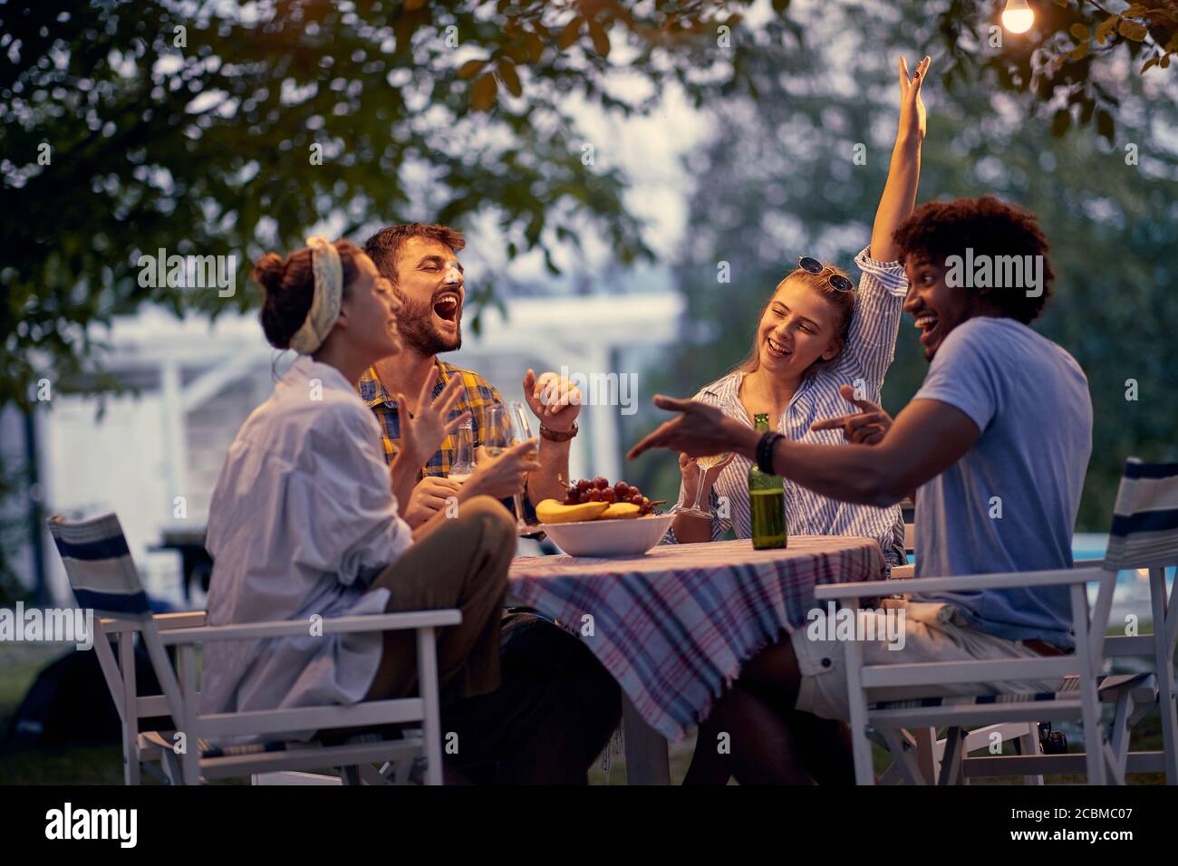 Giovani amici sorridenti al picnic dopo il tramonto. Foto Stock