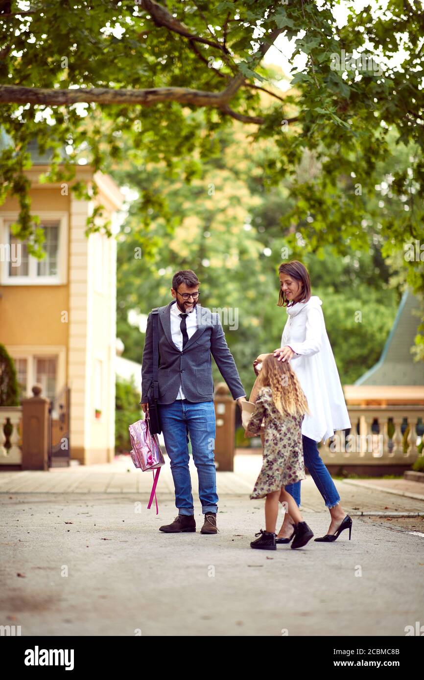 Mamma e papà camminano con la figlia dopo la scuola Foto Stock