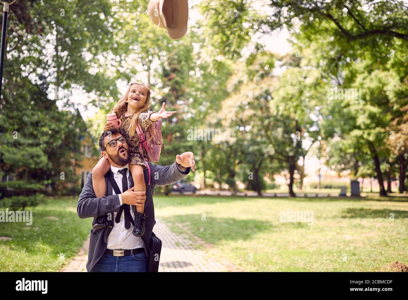 Padre che dà la figlia piggyback giro dopo la scuola Foto Stock