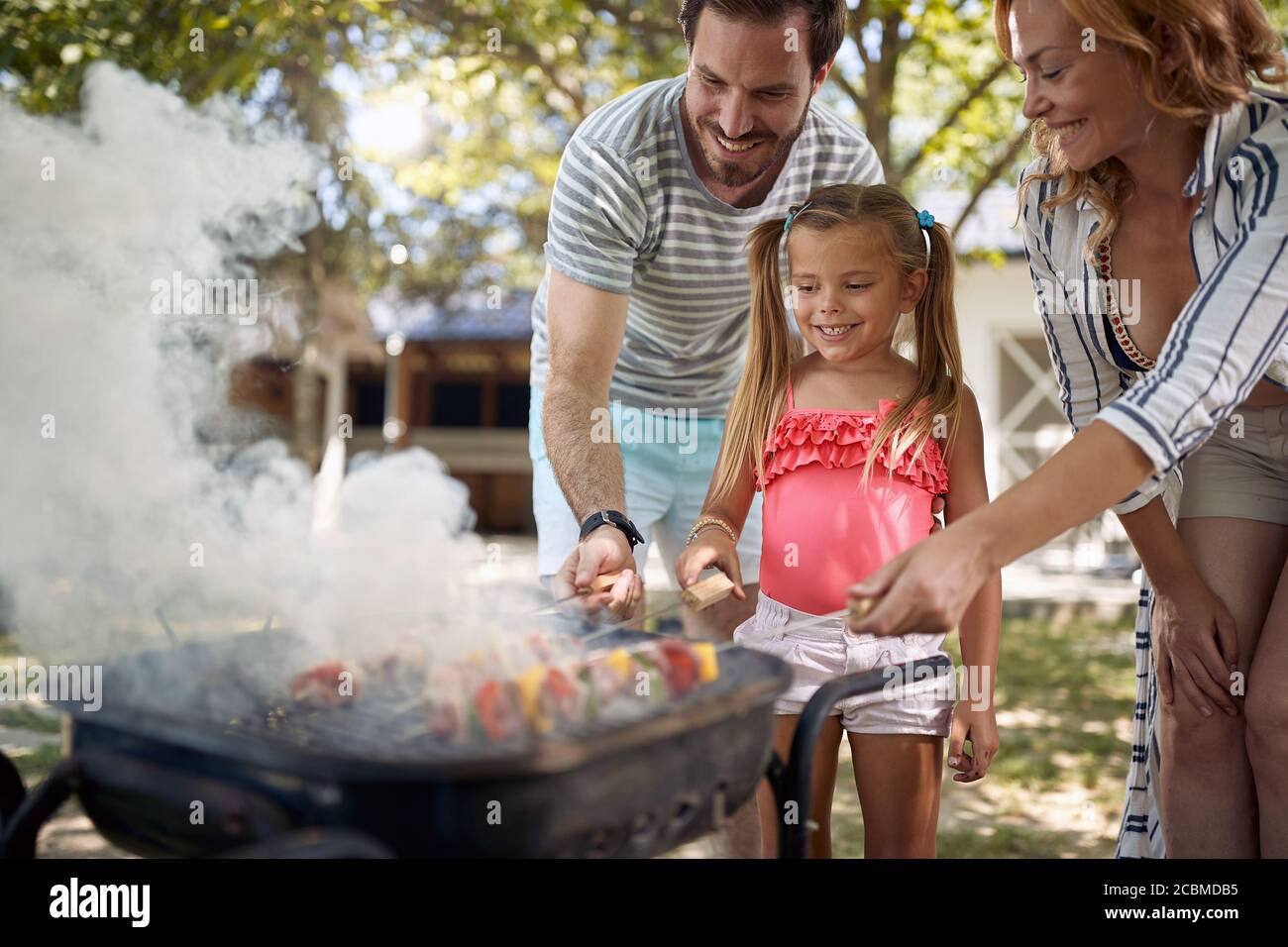 Buona famiglia all'aperto sul barbecue in giardino, grigliate. Foto Stock