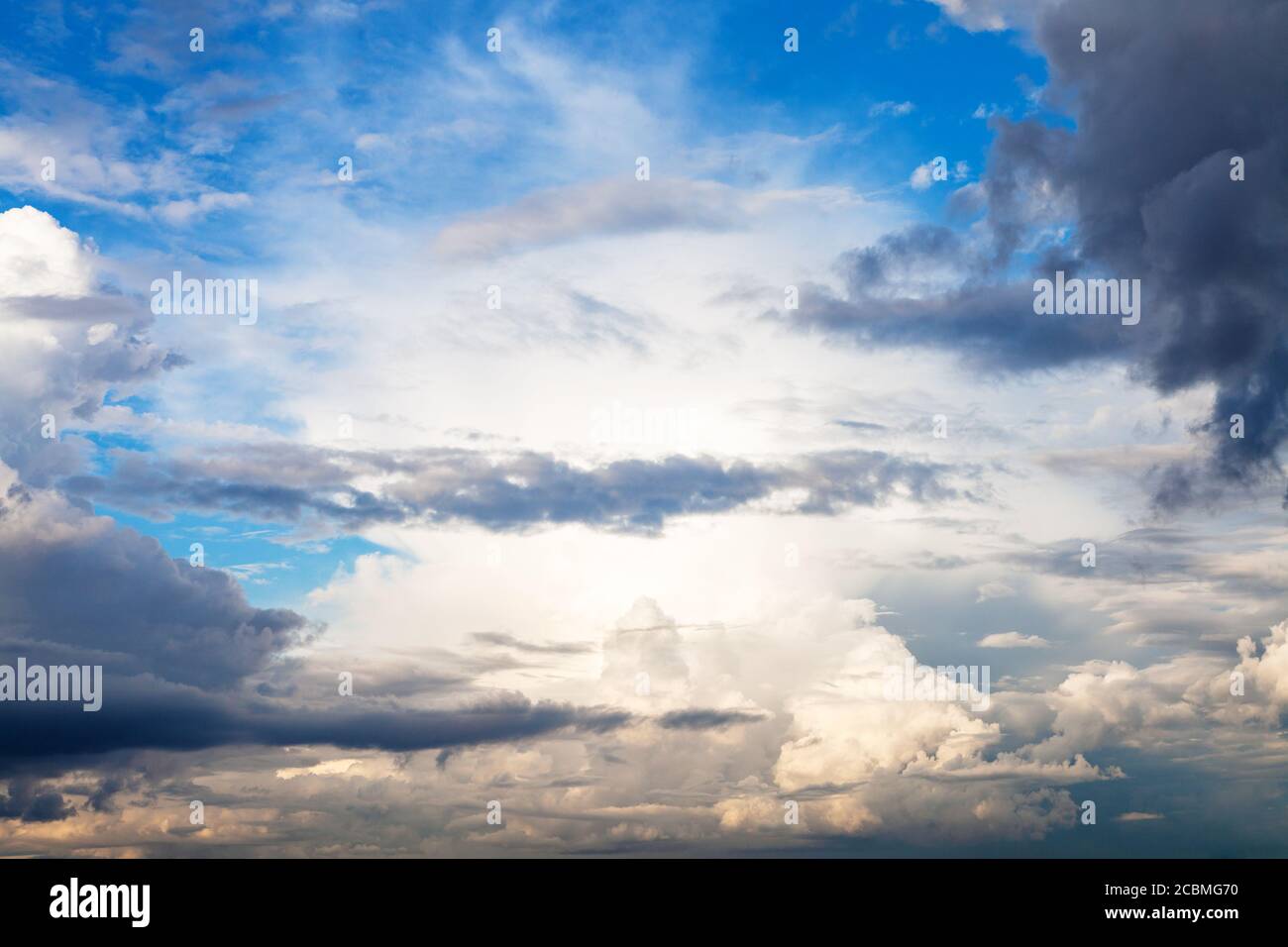 sole bloccato da nuvole di pioggia in cielo blu in estate sera Foto Stock