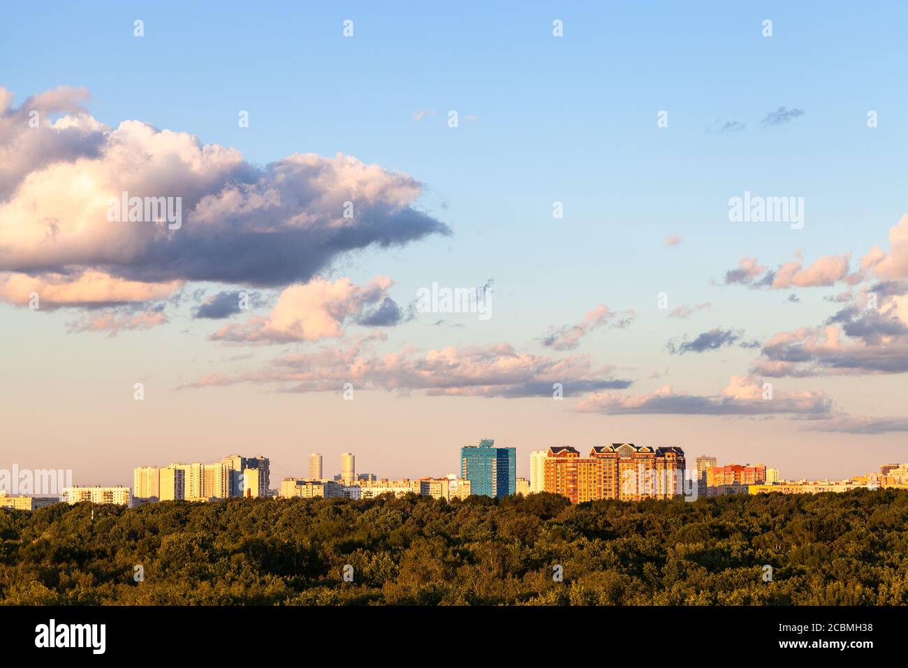 cielo blu e rosa tramonto con nuvole grigie e sopra città e verde foresta in estate soleggiata sera Foto Stock