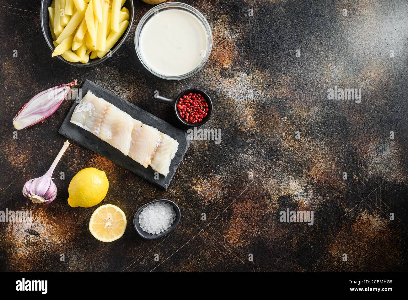 Filetto di merluzzo crudo e altri ingredienti biologici ricetta pesce e patatine e birra paster, potatoe, shallotaglio, sale, pepe su metallo rustico testurizzato Foto Stock