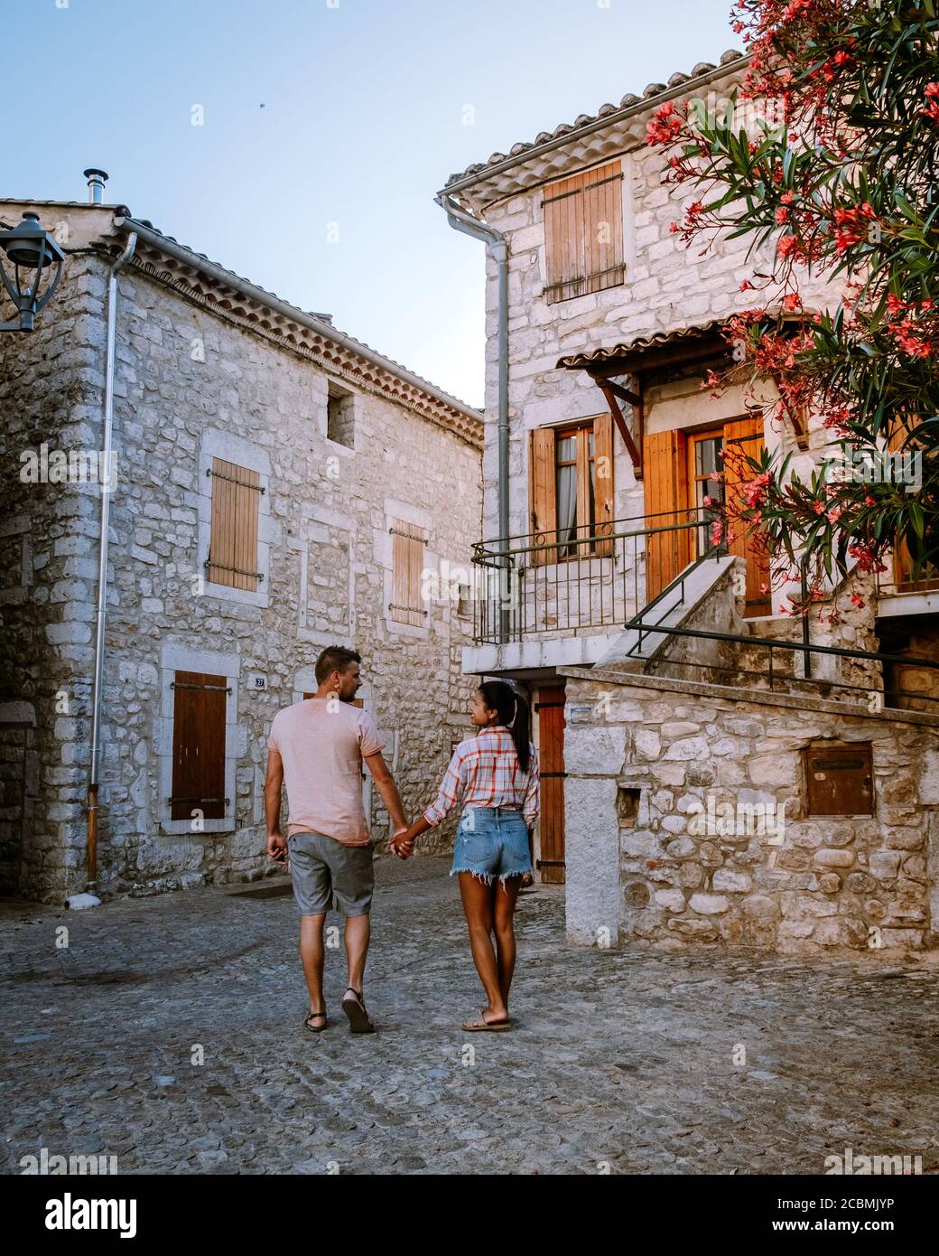 Una coppia visita Ruoms, il borgo medievale di Ruoms con le sue vecchie case in mattoni e i piccoli vicoli sul fiume Ardeche in Francia Foto Stock