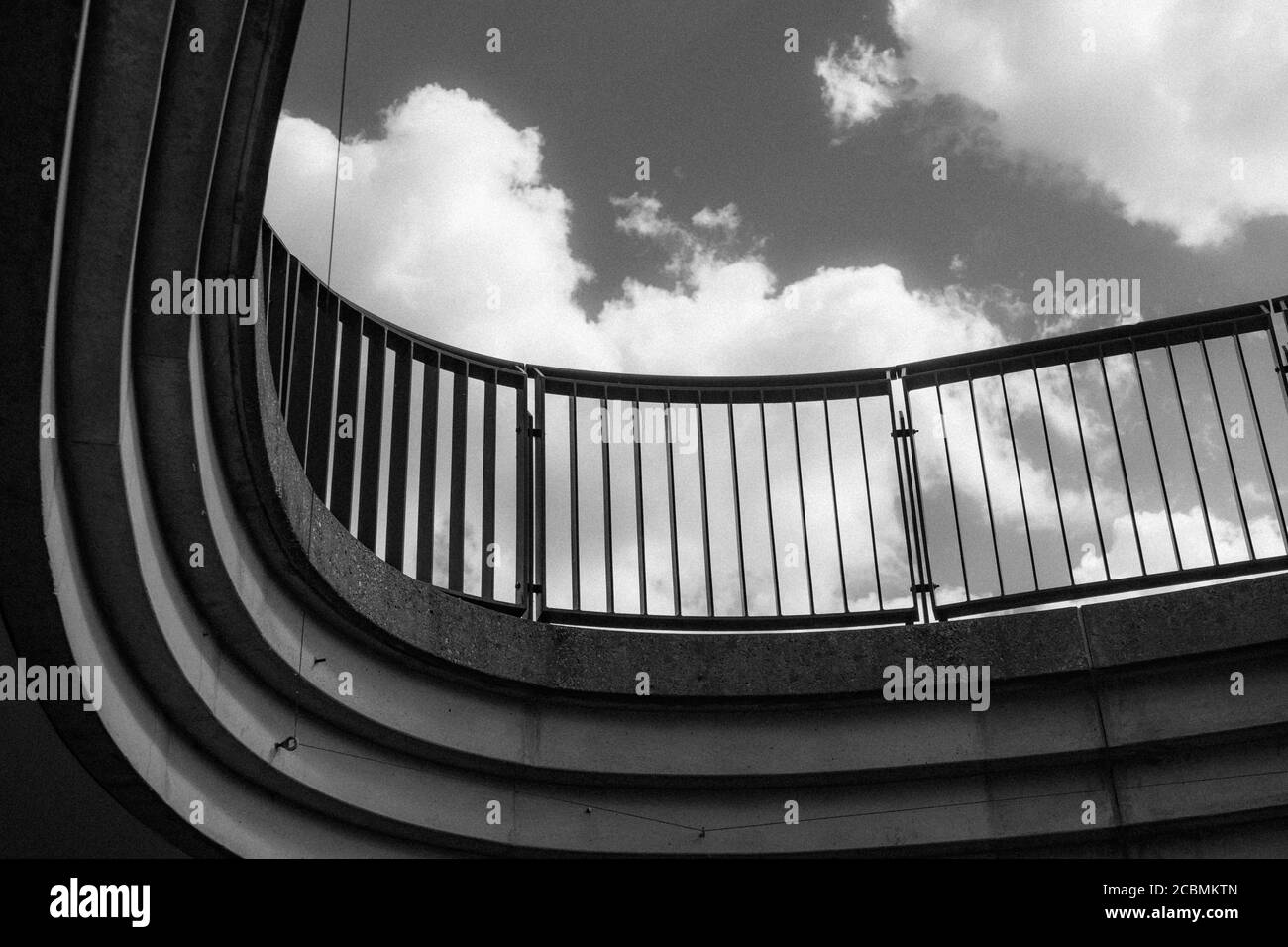 Moderno ponte curvo girato contro un cielo blu con nuvole In bianco e nero Foto Stock