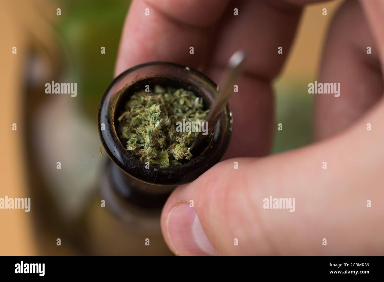 Uomo che tocca il bong con la cannabis trinciata. Fumare marijuana Foto Stock