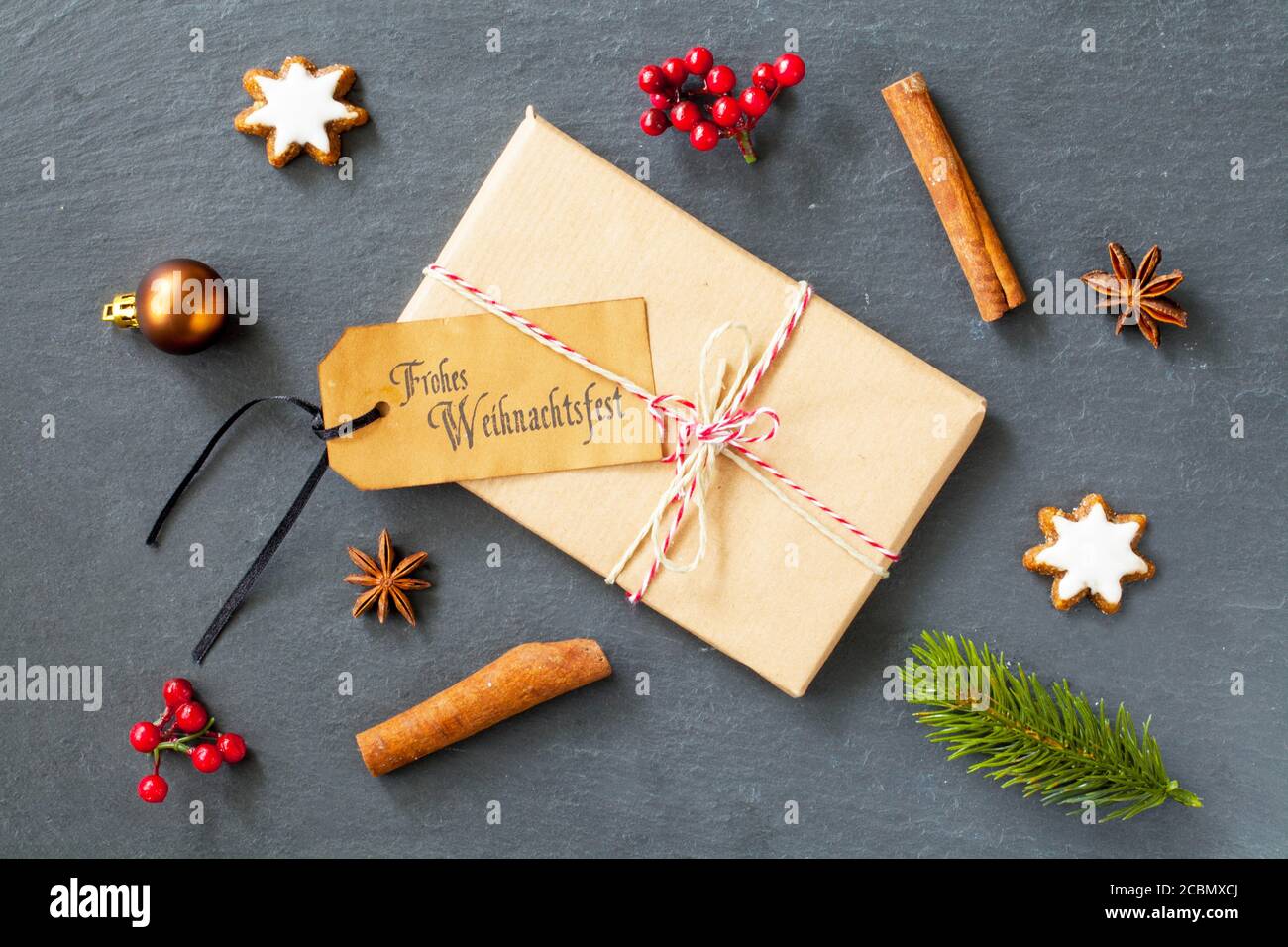 Confezione regalo con un tag 'Frohe Weihnachtsfest - buon Natale' su di esso sul tavolo con decorazioni Foto Stock