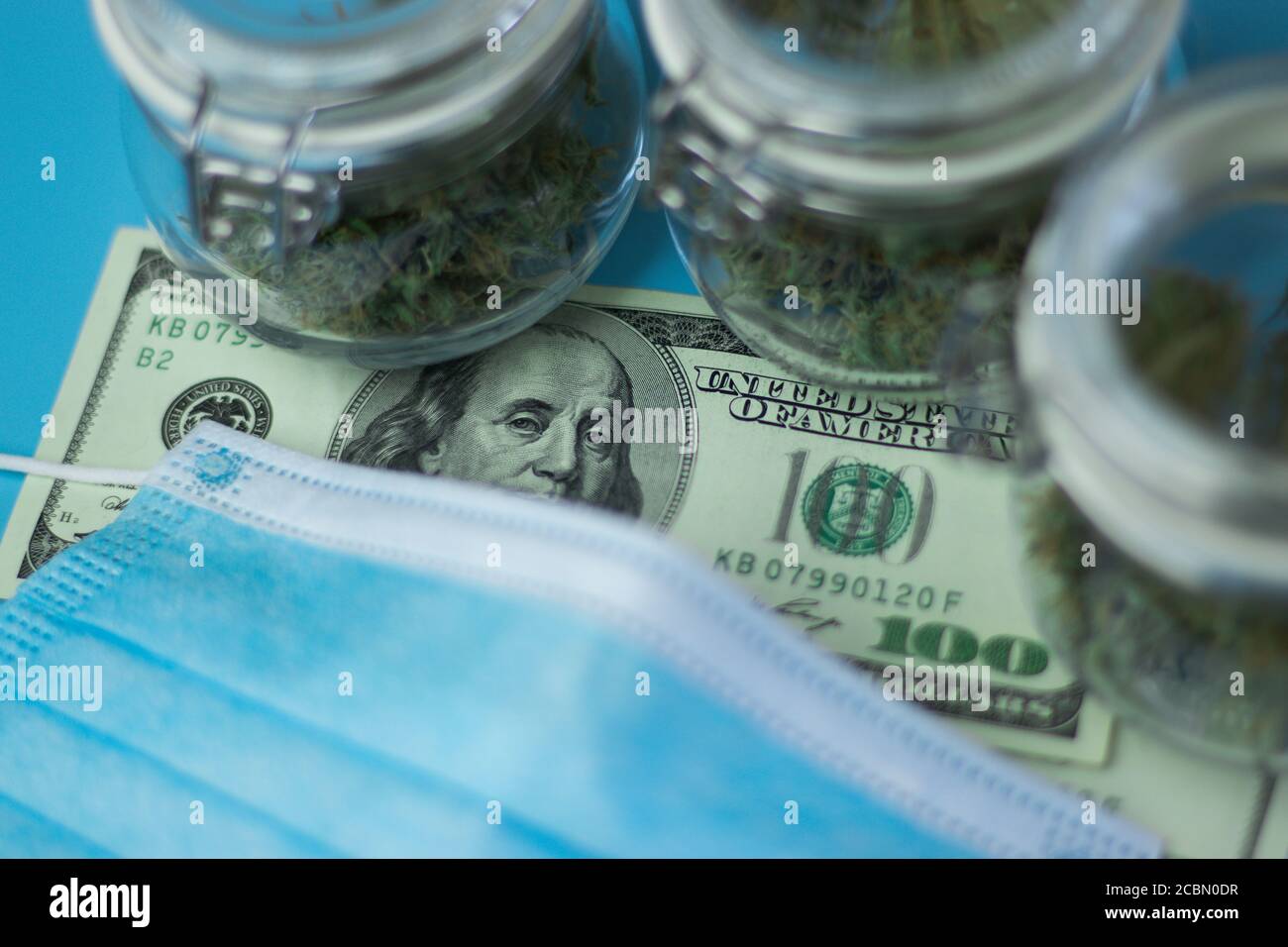 Maschera di protezione della salute, denaro in dollari e cannabis Foto Stock