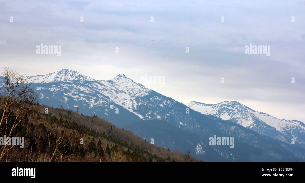 Le creste della montagna ricoperta di neve e cielo nuvoloso. Foto Stock
