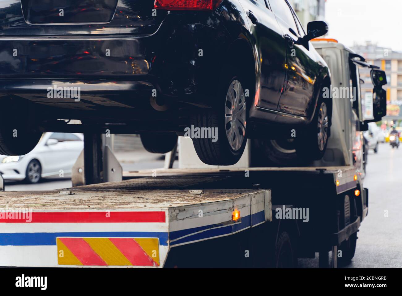 Auto rotta nera su un autocarro di traino. Primo piano Foto. Problema meccanico del veicolo o parcheggio errato su strada. Foto Stock