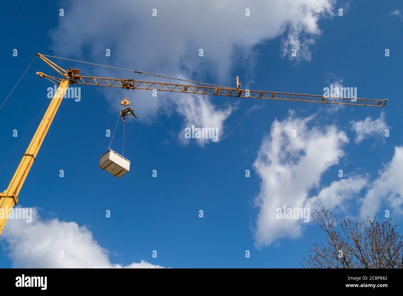 Sollevatore o gru mobile su cielo nuvoloso in città utilizzato per lavori di costruzione o lavori. Industria edile, movimentazione di materiali pesanti. Foto Stock
