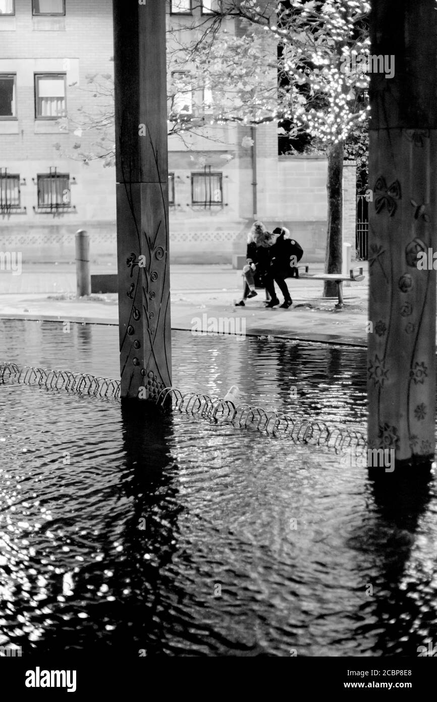 Colonne architettoniche sull'acqua, una coppia si siede insieme sullo sfondo, fotografia di strada, città di notte, parchi cittadini, luoghi di riposo Foto Stock