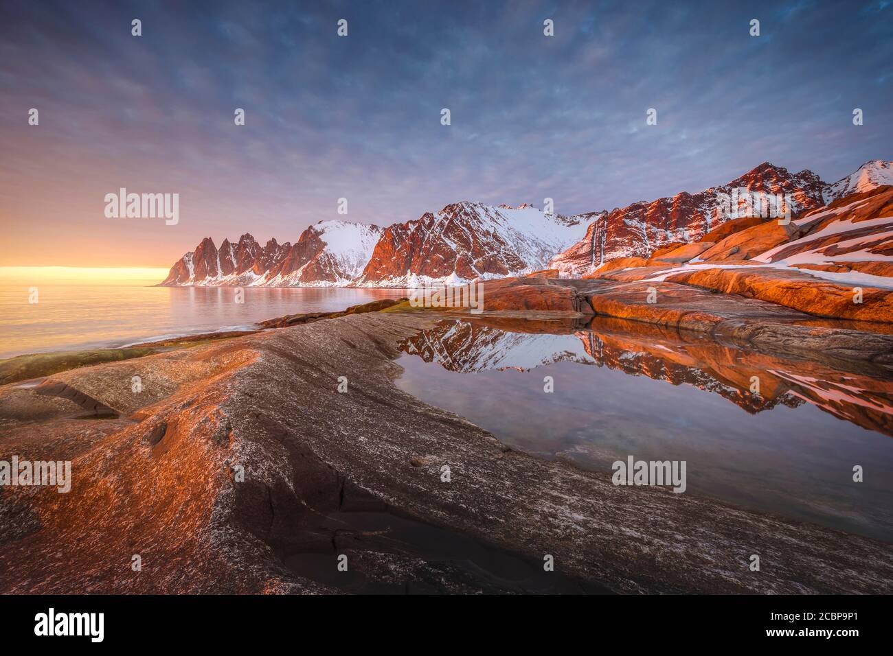 Spiaggia rocciosa di Toggeneset, picco roccioso Devils denti, diavolo denti, Okshornan, in caldo sole, fiordi di pietra, Isola di Senja, Troms, Norvegia Foto Stock