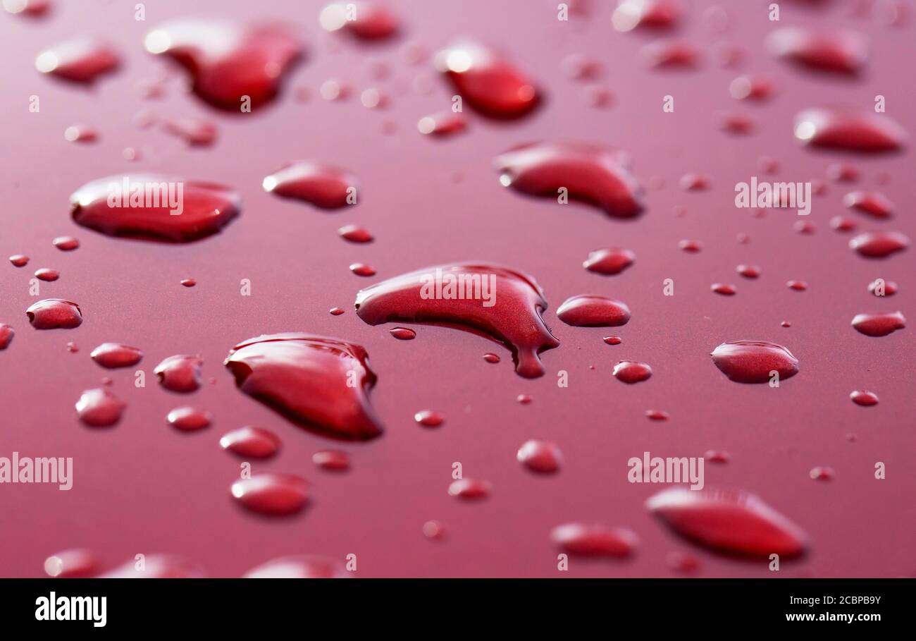Gocce di pioggia su vernice rossa dell'automobile, Austria Foto Stock