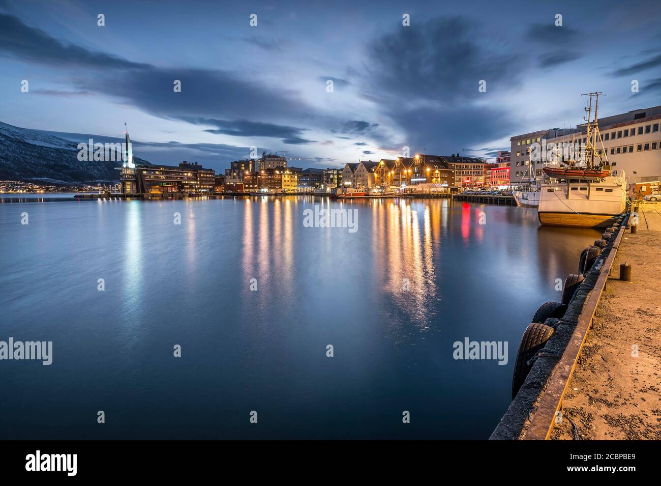 Città e porto con riflessione in mare, Tromsoe, Troms, Norvegia Foto Stock
