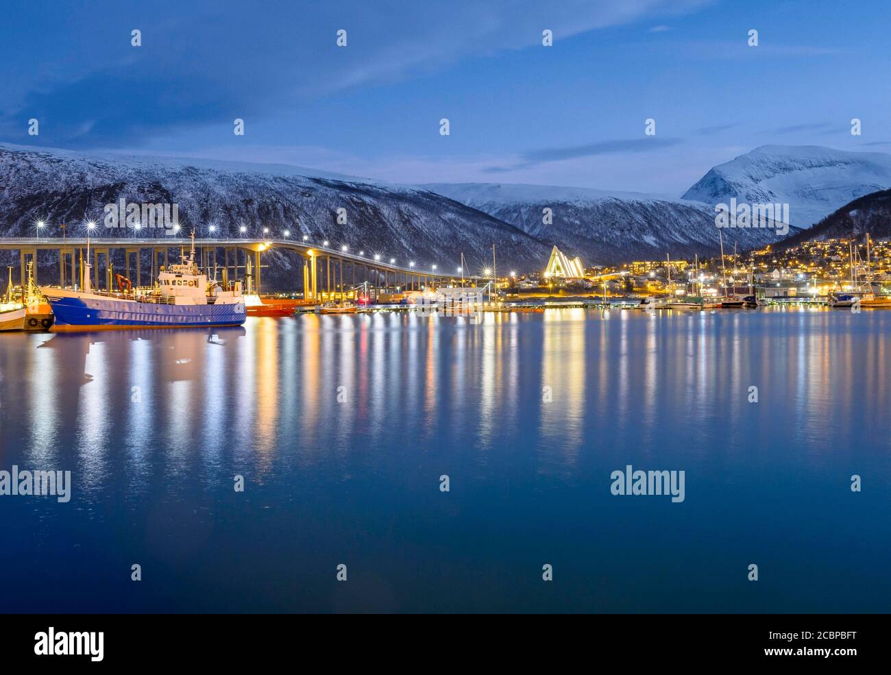 Vista sul porto e sulla città con il ponte di Tromsobrua o Tromso, nella chiesa posteriore di Tromsdalen, la cattedrale del Mar Artico, Ishavskatedralen, al tramonto Foto Stock