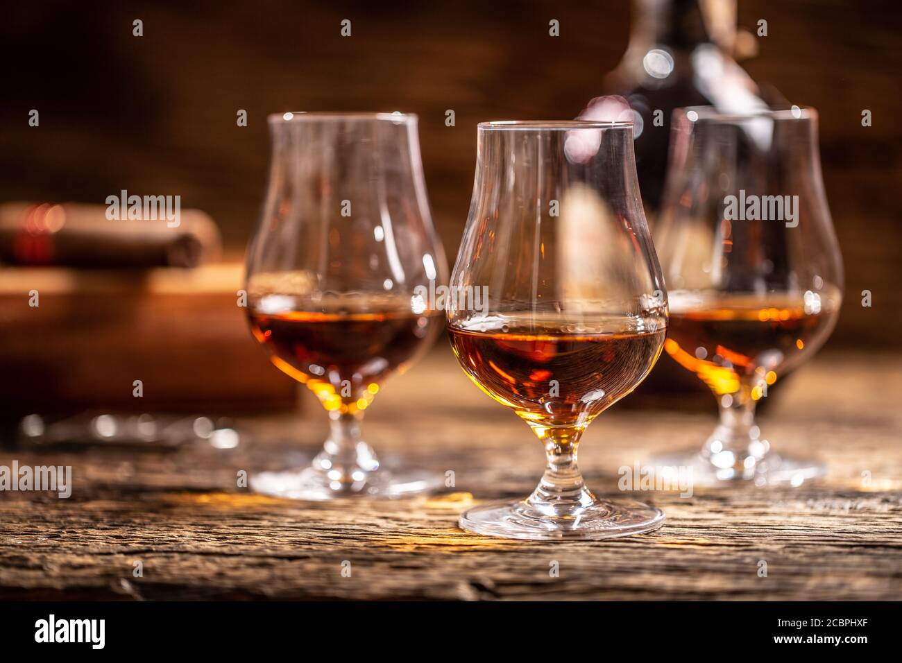 Rum caraibico in bicchieri moderni con una bottiglia di rum e un sigaro sullo sfondo Foto Stock