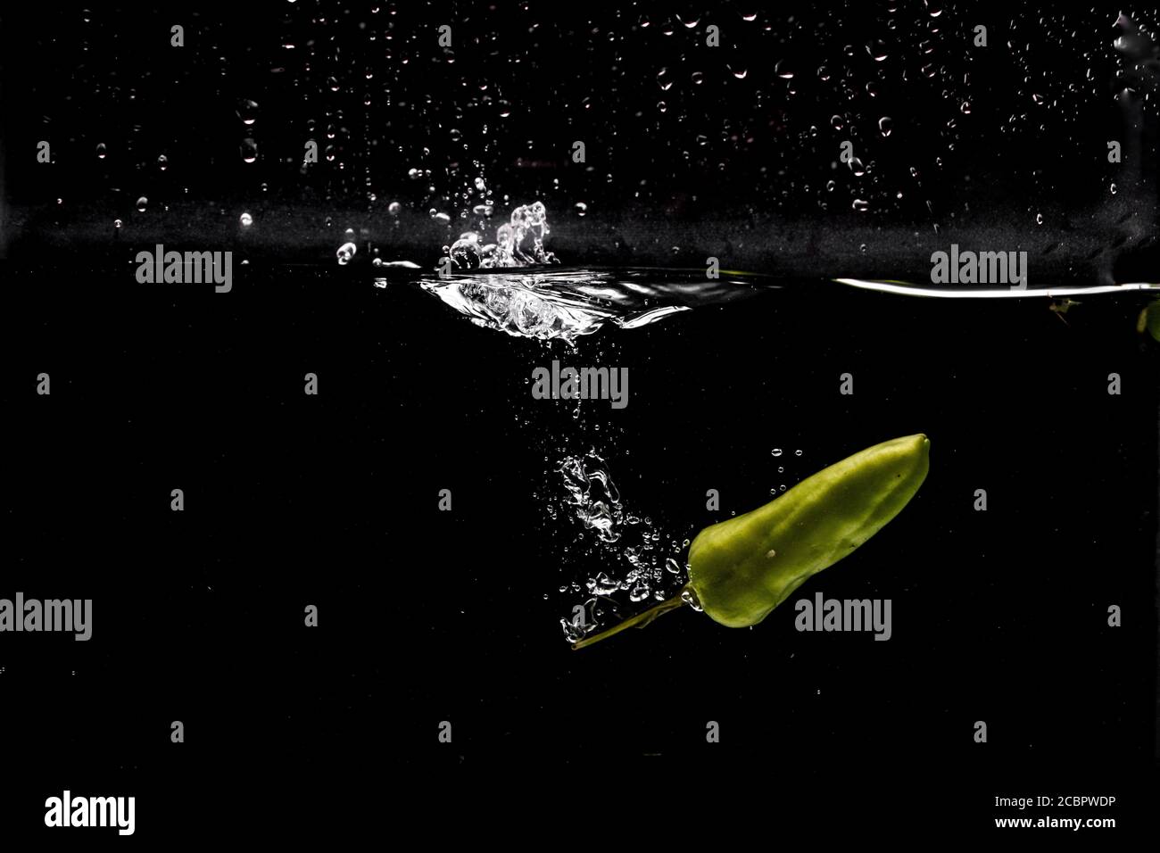 Freeze Motion di peperoni Jalapeno con acqua Splash su nero sfondo Foto Stock