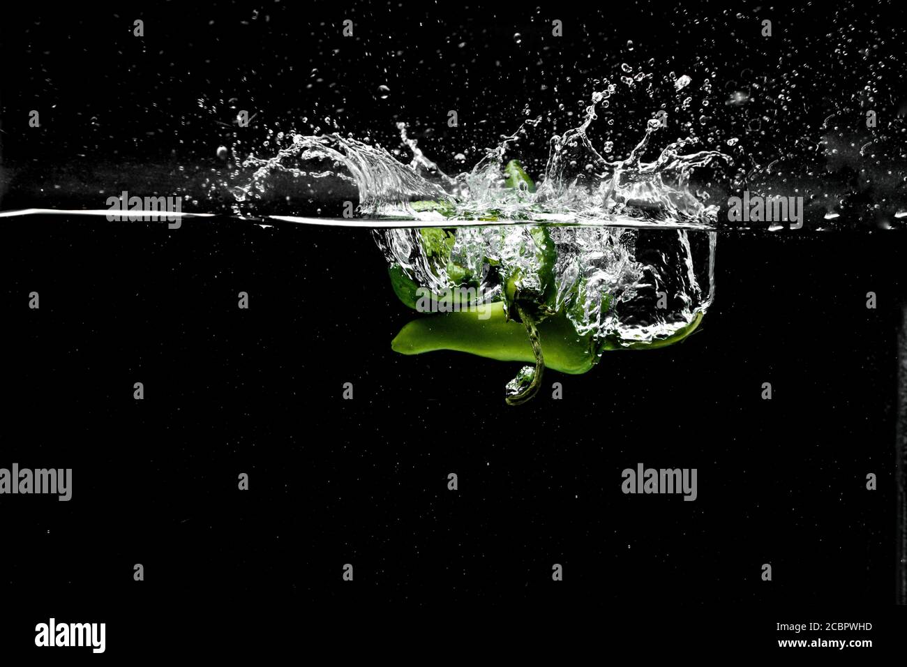 Freeze Motion di peperoni Jalapeno con acqua Splash su nero sfondo Foto Stock